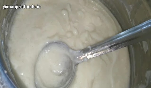 A steel container with Homemade Curd and a steel spatula